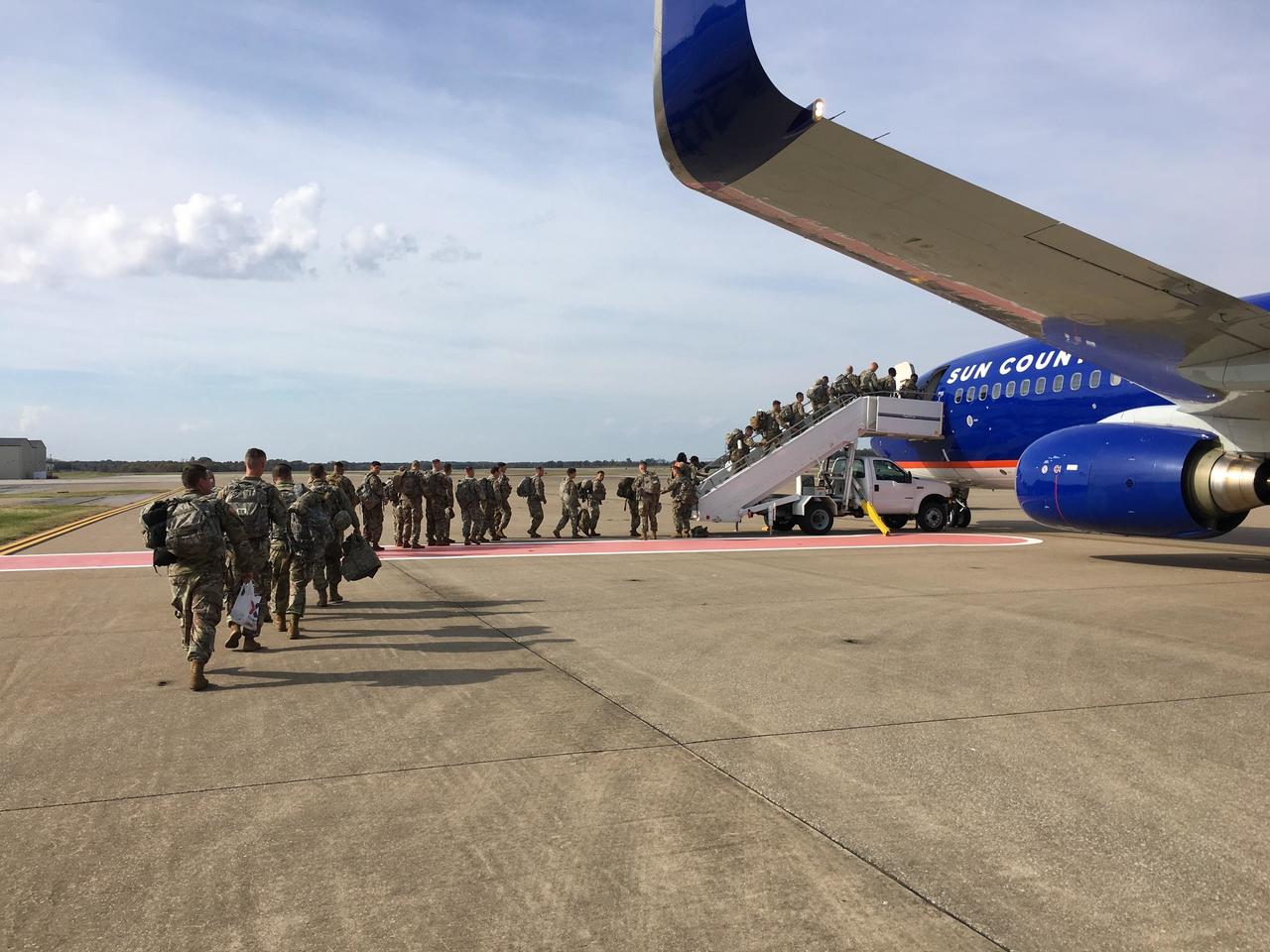 Ya marchan. Varios militares suben a un avión para dirigirse a la frontera con México. (EFE)