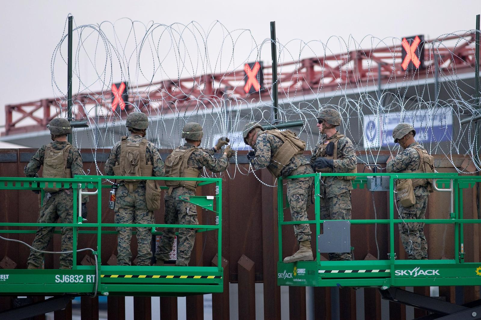 Refuerzo. Militares de EU instalan cable de concertina en la parte superior del muro entre EU y México, en San Diego. (EFE)