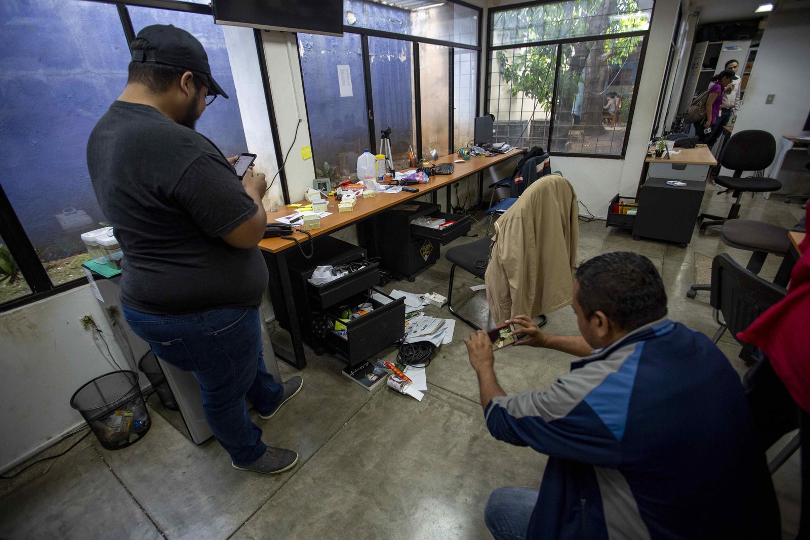Afectados. Dos periodistas toman fotografías de una oficina del semanario Confidencial de Nicaragua.
