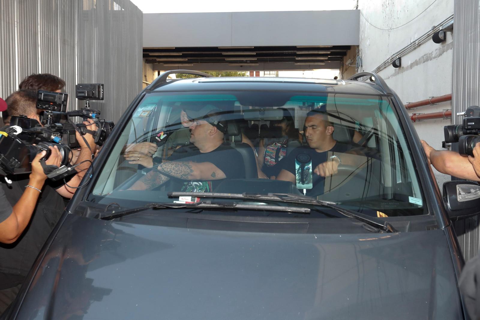 El exfutbolista argentino Diego Maradora (i-atrás, parcialmente cubierto) responde preguntas de la prensa desde el interior de un vehículo mientras se retiraba de la Clínica Olivos, ayer en Buenos Aires. (ARCHIVO)