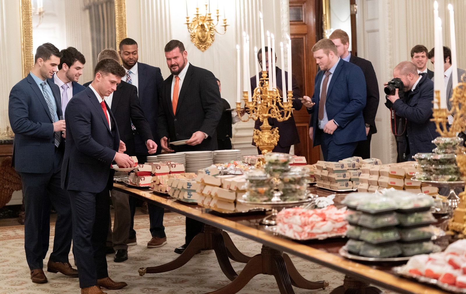 Los miembros del equipo de futbol americano Clemson Tigers, campeones nacionales universitarios, se preparan para cenar comida rápida servida por el presidente de los Estados Unidos, Donald J. Trump.