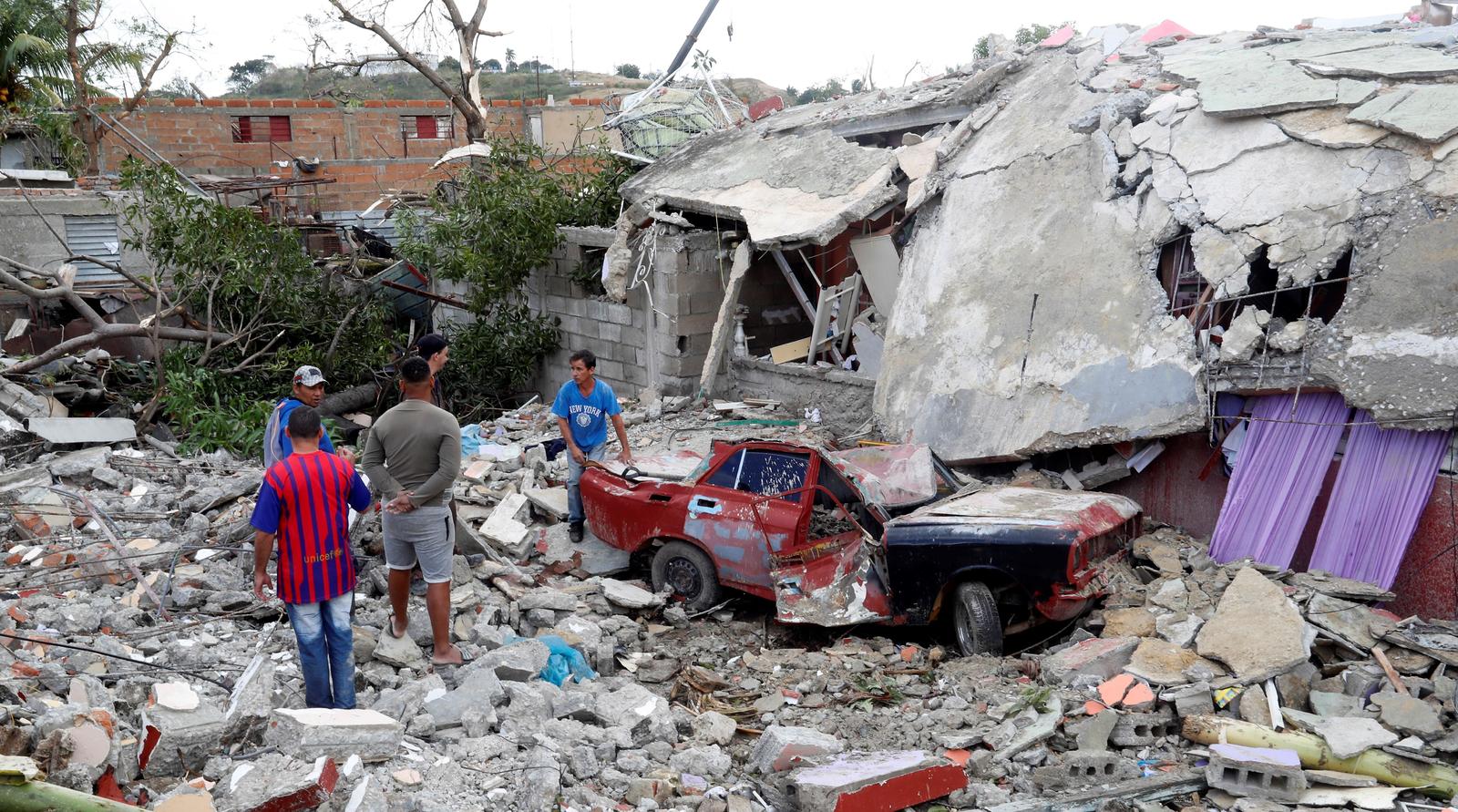 Labores. Varias personas tratan de sacar un auto que quedó bajo los escombros luego del paso de un tornado ayer, en La Habana. (EFE)