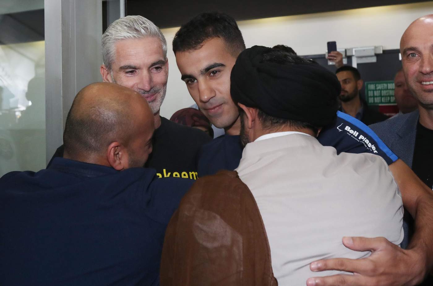 El futbolista refugiado Hakeem Al-Araibi (c) llega a Melbourne, acompañado del excapitán de la selección nacional de Australia, Craig Foster.