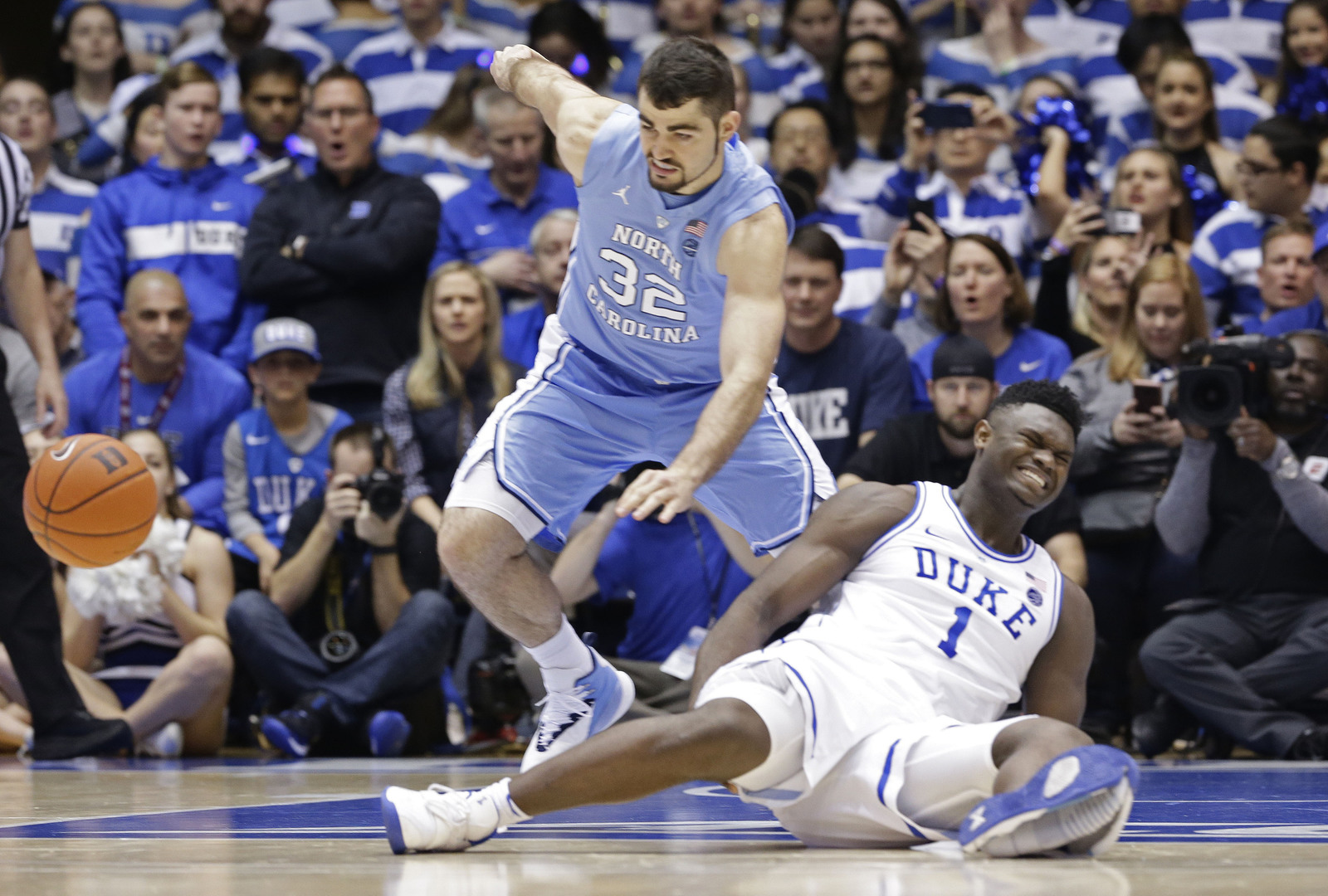 Zion Williamson (1), de Duke, queda en el piso tras lesionarse en una jugada ante Luke Maye, de North Carolina, en el basquetbol universitario en Durham, Carolina del Norte.