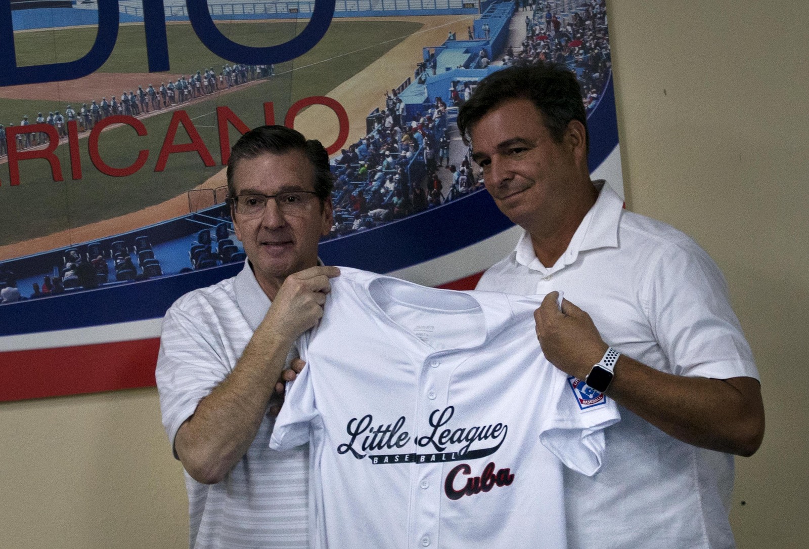Stephen D. Keener (i), presidente de la organización internacional de las Pequeñas Ligas, le entrega una camiseta a Antonio Castro, el hijo del fallecido presidente cubano Fidel Castro.