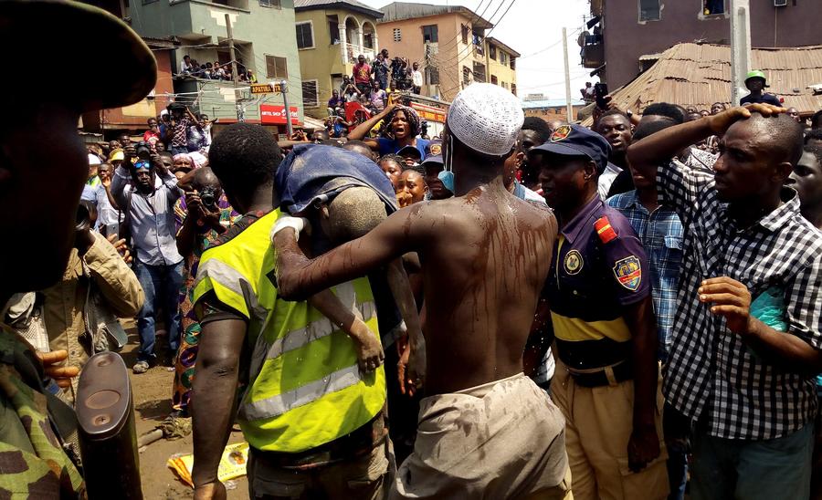 Miembros de los equipos de rescate portan a un niño encontrado entre los restos de un edificio derrumbado ayer en Lagos. (EFE)