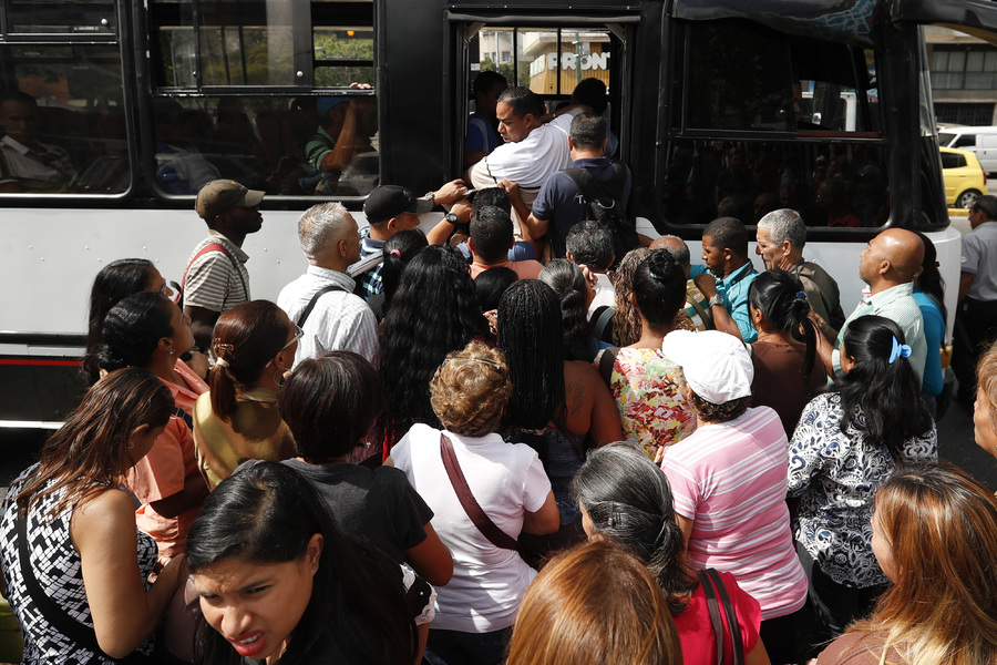 Los pasajeros se apresuran para abordar un autobús en Caracas para regresar a sus actividades laborales luego del apagón. (AP)