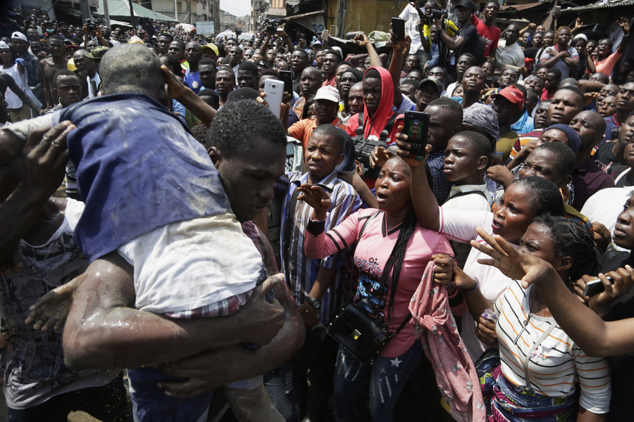 Un hombre saca en brazos a un niño rescatado de entre los escombros tras el derrumbe de un edificio en Lagos, Nigeria. (AP)