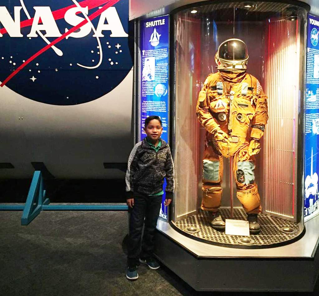 Iker Mota, posa junto con un traje espacial como parte de su recorrido en el Space Center de Houston, Texas. (EL SIGLO DE TORREÓN)