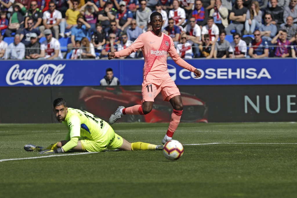 El delantero de Barcelona Ousmane Dembele dispara a puerta con el portero de Huesca, Roberto Santamaría, vencido en el suelo, en partido de La Liga.