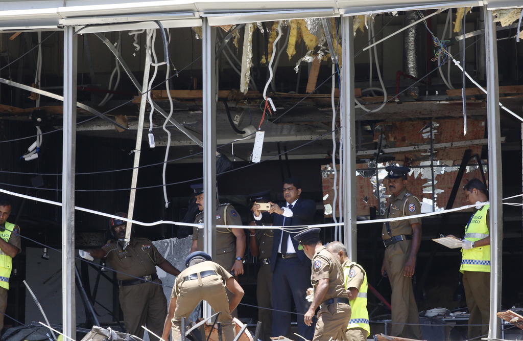 Un policía esrilanqués inspecciona el sitio donde se produjo una explosión en el hotel Shangri-la en Colombo, Sri Lanka. (EFE y AP)