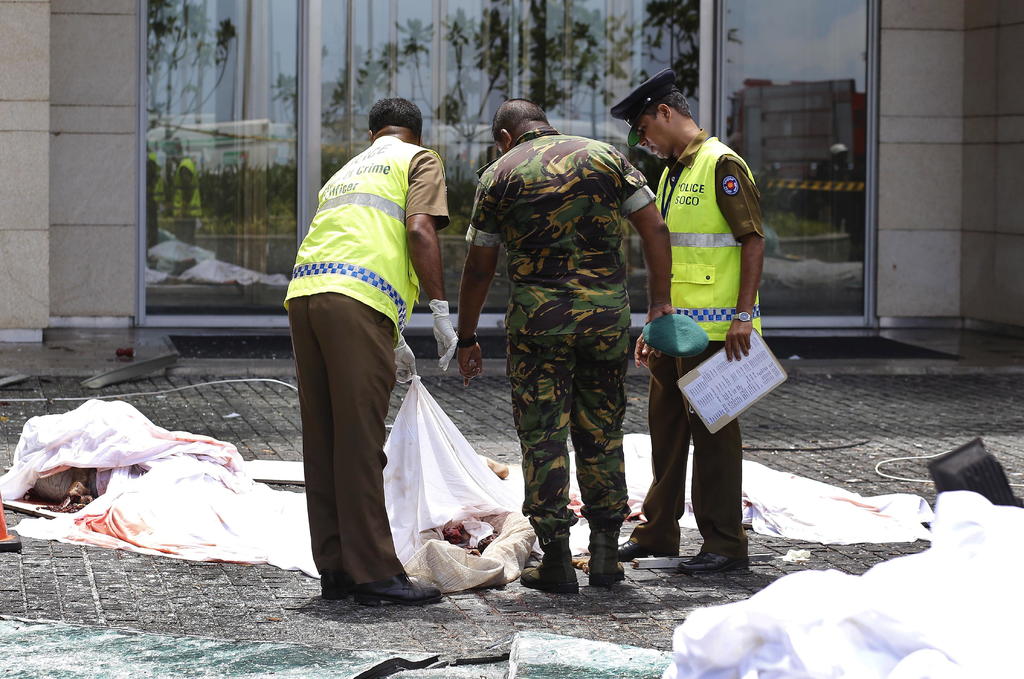 La policía y el personal de seguridad inspeccionan los restos de las víctimas en la escena después de una explosión en un hotel. (EFE y AP)