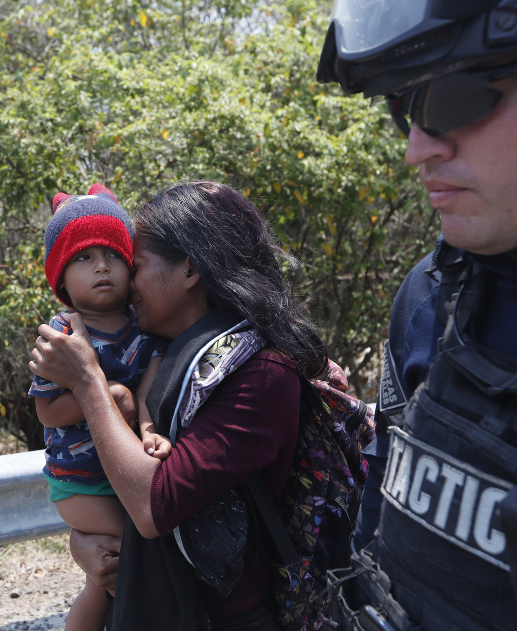 Una mujer migrante centroamericana y su hijo caminan con un agente de la Policía federal mientras son detenidos en la carretera a Pijijiapan, Chiapas. (AP)