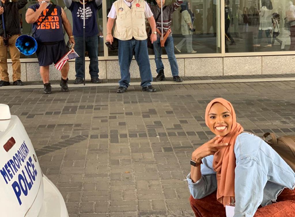 Shaymaa Ismaa’eel, musulmana, posa con una sonrisa frente a manifestantes en contra de aquella fe. (INTERNET)