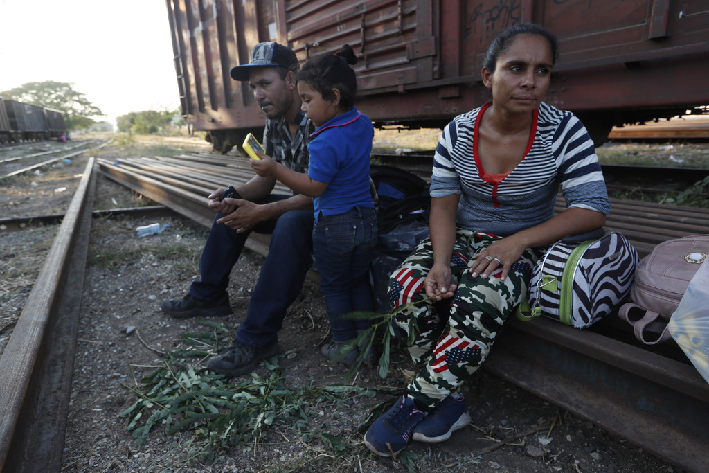 Losmigrantes hondureños SandraMontoya, su esposo, JoséVallecillo, y su hija Brittany descansan sobre unas vías antes de que el tren de carga parta de Arriaga. (AP)