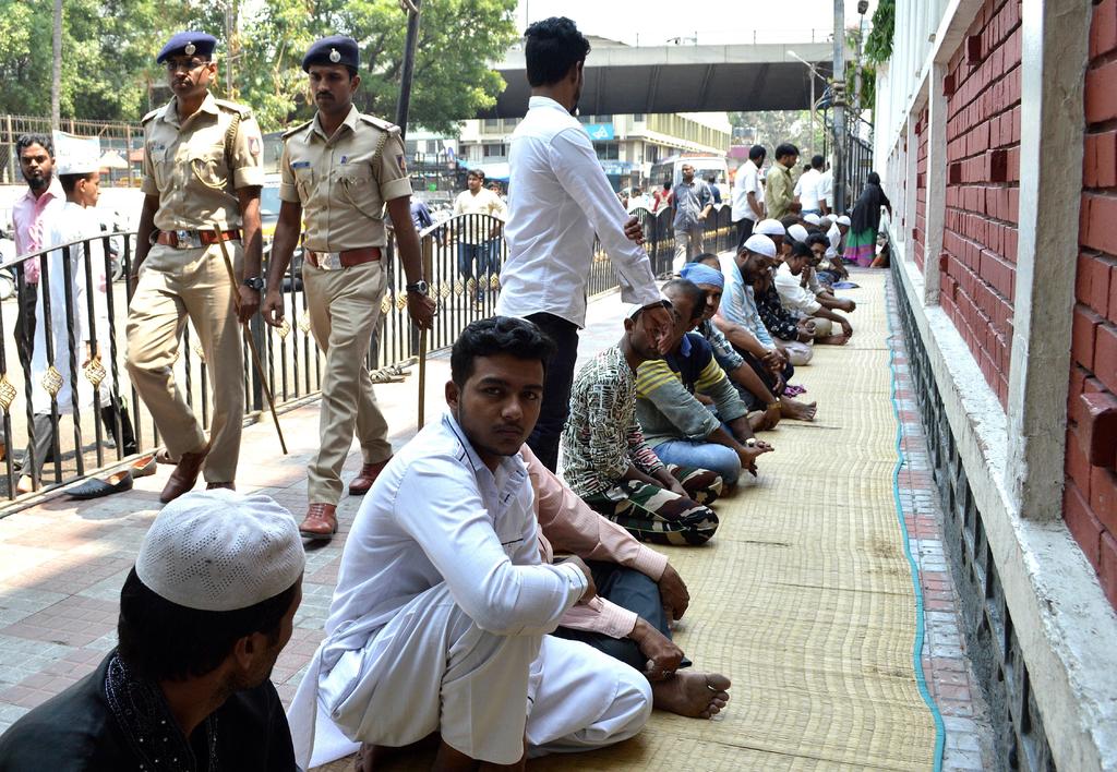 Dos agentes de policía caminan tras un grupo de indios musulmanes que rinde homenaje a las víctimas del atentado de Sri Lanka.