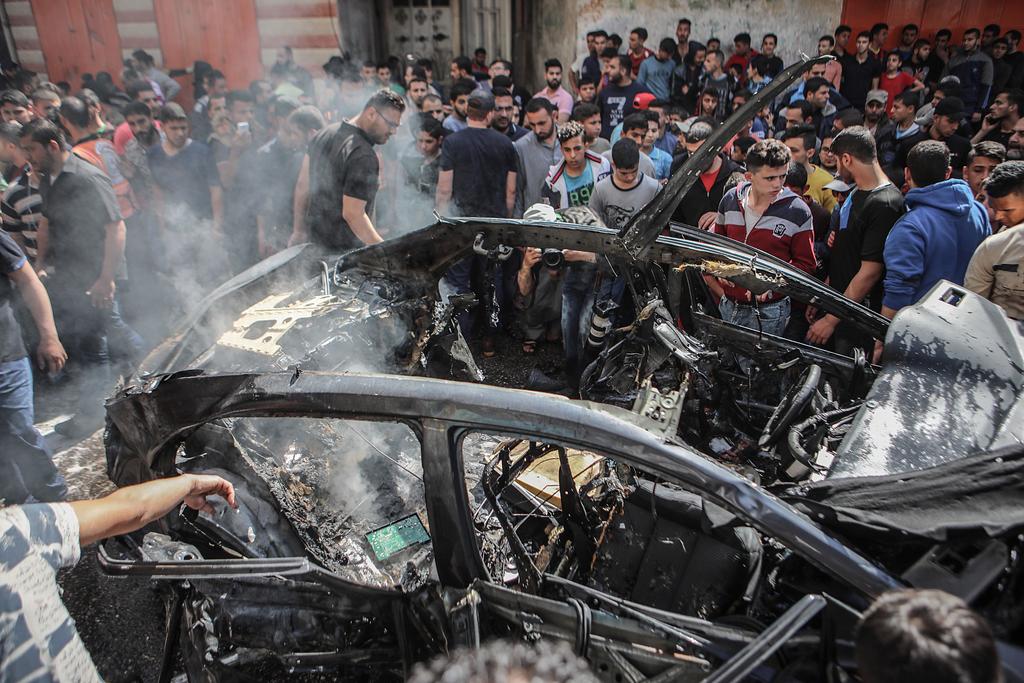 Palestinos inspeccionan el automóvil destruido del miembro de Hamás Hamed Al-Khodari después de ser golpeado por un ataque aéreo israelí en la ciudad de Gaza, ayer. (EFE)