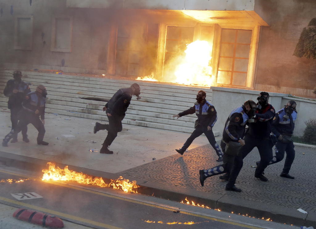 Oficiales de policía huyen luego de que una bomba improvisada fue lanzada cerca de ellos fuera de un edificio de Gobierno. (EFE)