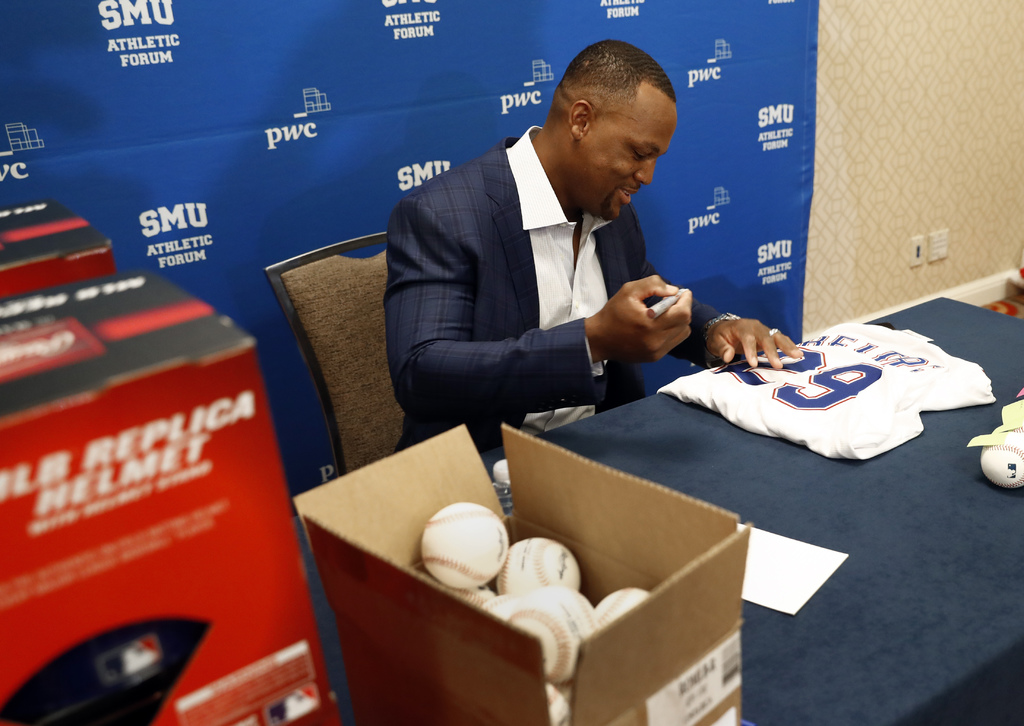 Adrián Beltré, exjugador de las Grandes Ligas, firma algunos autógrafos en memorabilia deportiva antes del inicio de una conferencia durante el Foro Atlético de SMU en Dallas, Texas. (AP)