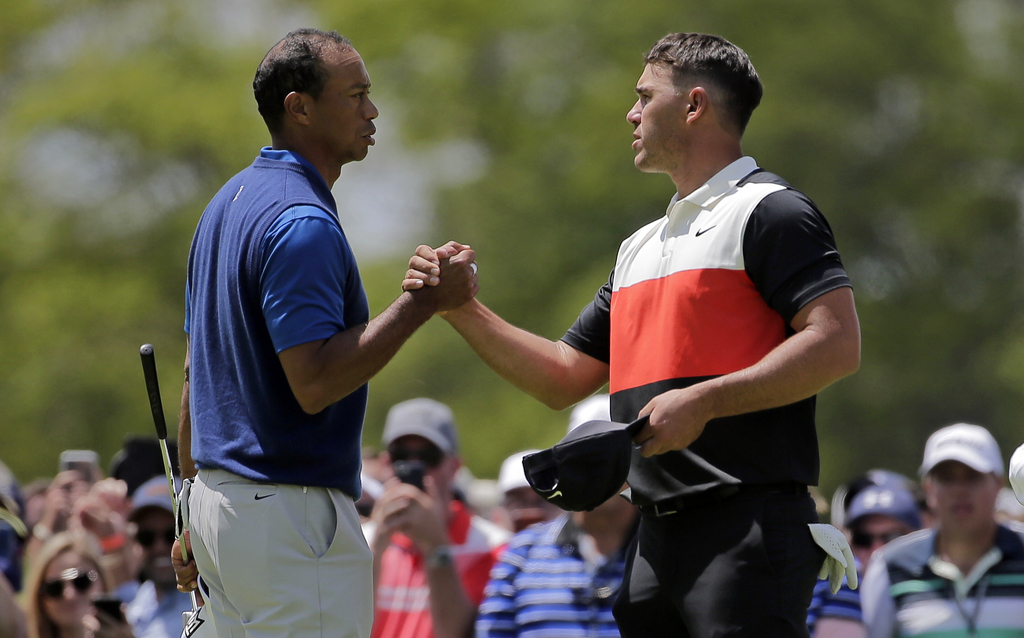 Tiger Woods (i) y Brooks Koepka (d) se saludan tras completar la primera ronda del Campeonato de la PGA. (AP)