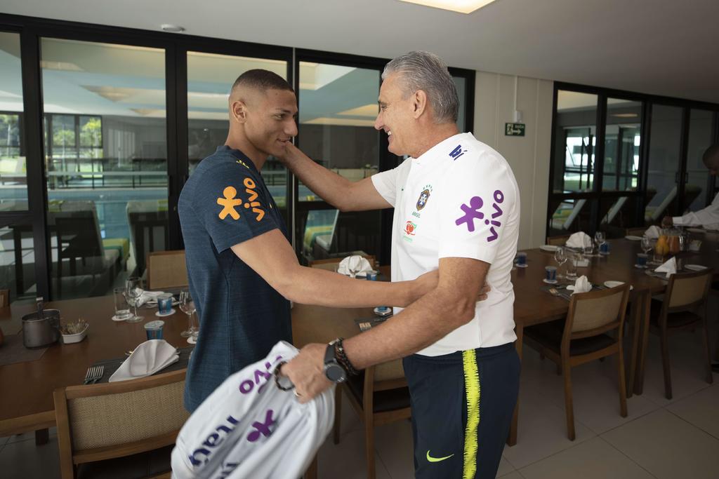 Adenor Leonardo Bacchi 'Tite' (d) saluda al atacante Richarlison a su llegada ayer a la concentración de la selección brasileña. (EFE)