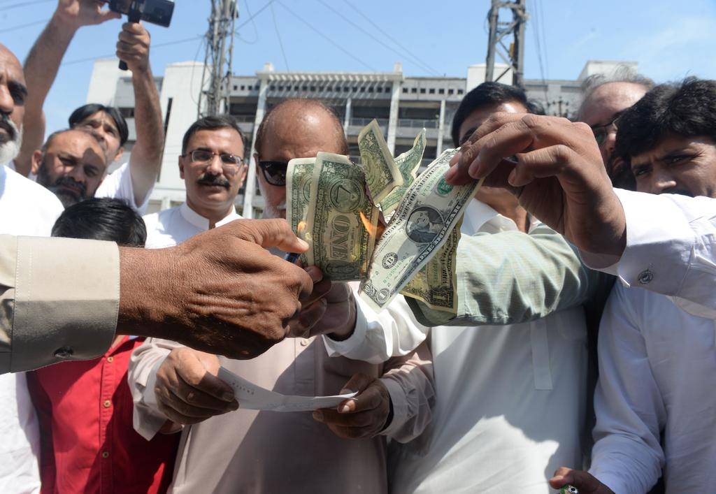 El desprecio por la moneda estadounidense se manifestó ayer en Pakistán, donde quemaron billetes. (ARCHIVO)