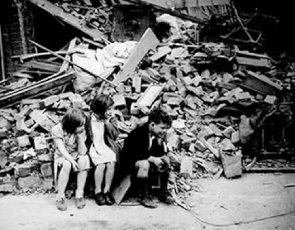 Niños barceloneses sentados sobre los escombros después de un bombardeo.