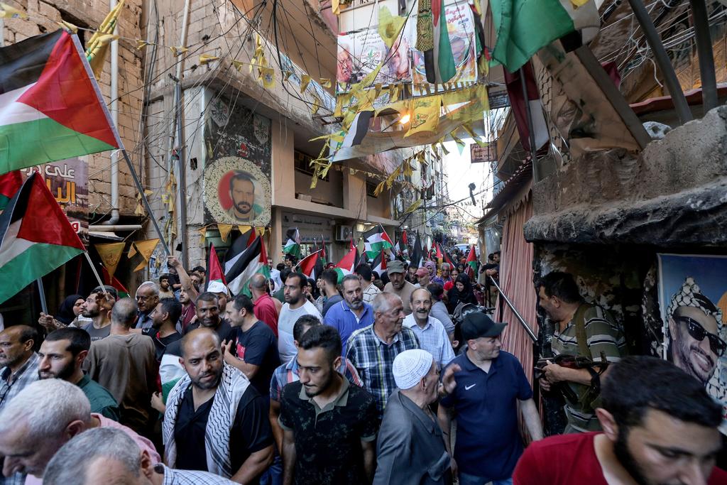 Palestinos ondean banderas nacionales y gritan consignas durante manifestación contra apoyo estadounidense. (EFE)