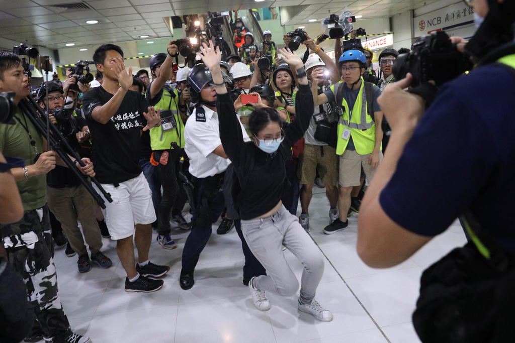 Una mujer es arrestada por los policías mientras decenas de periodistas toman fotografías. (EFE)