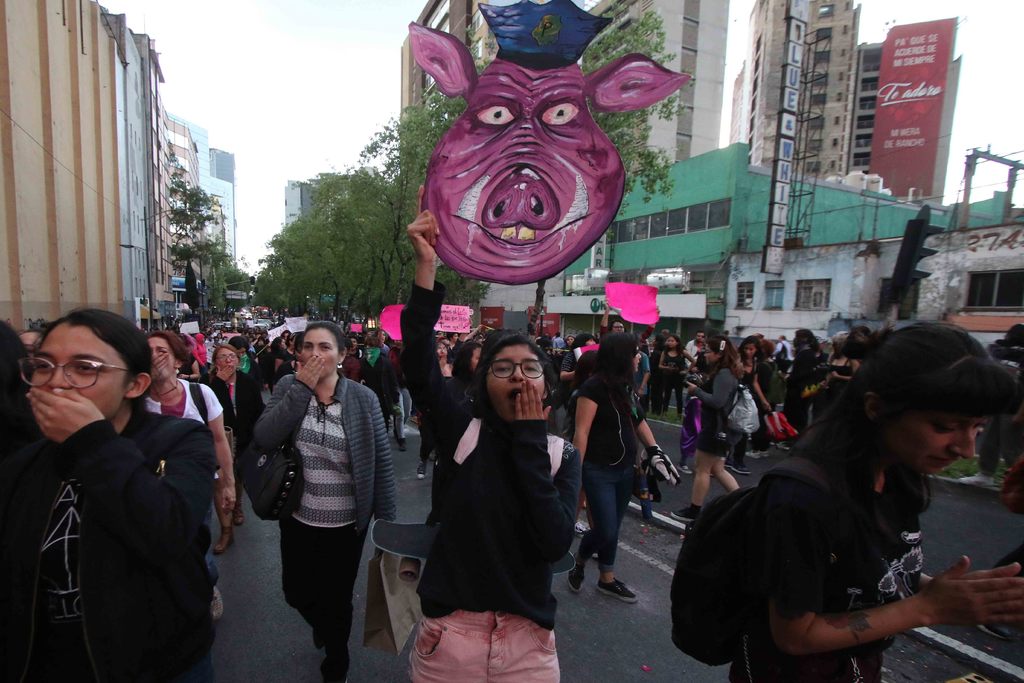 Una joven sosteniendo un rostro de un cerdo con indumentaria policiaca, haciendo alusión a los elementos que presuntamente violaron a una joven de 17 años. (ARCHIVO)
