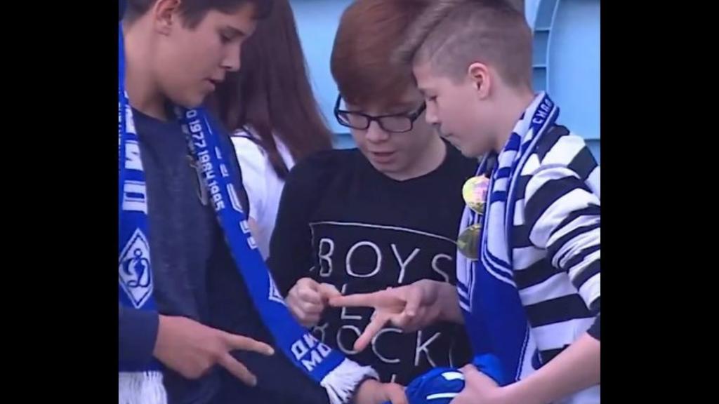 Tres niños en la grada definen quién se queda con la playera de un jugador de la Liga Premier de Rusia. (ESPECIAL)