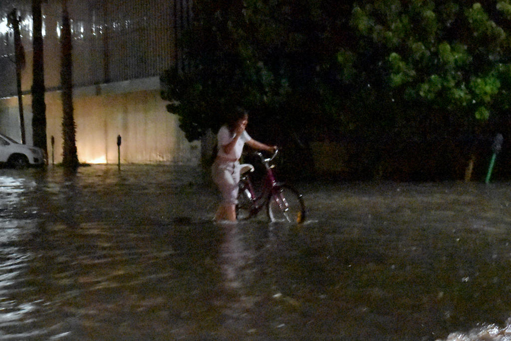 Algunas personas fueron sorprendidas por la lluvia en el primer cuadro de la ciudad y tuvieron que caminar entre el agua.