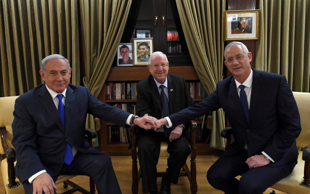 Netanyahu y Grantz dándose la mano frente al presidente de Israel. (EFE)