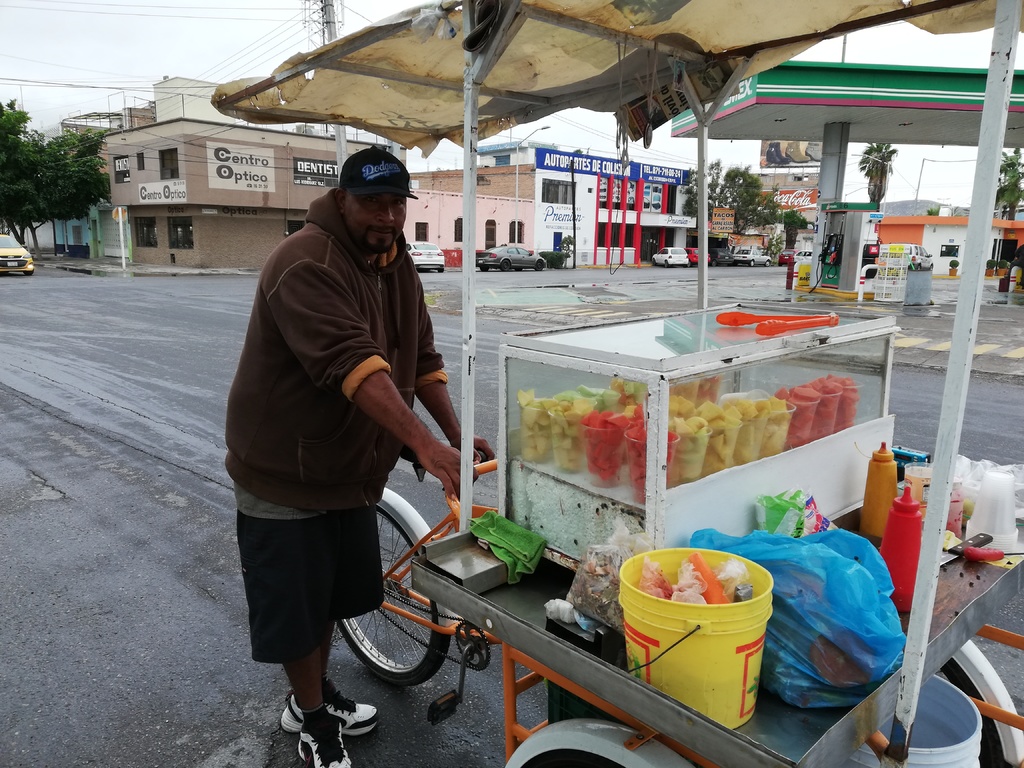 José espera vender sus vasos con frutas a usuarios de la subdelegación del IMSS, pese al fuerte frío. (VIRGINIA HERNÁNDEZ)
