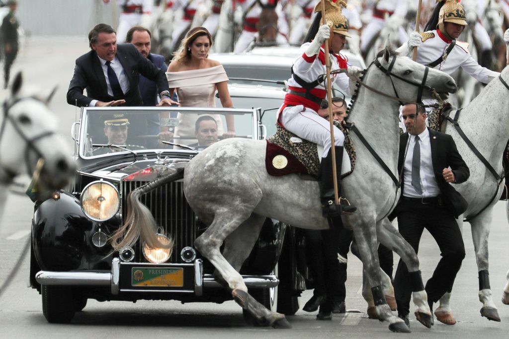 El presidente brasileño, Jair Bolsonaro (i), y su esposa Michele (c), observan a un caballo de la guardia presidencial que sufre un percance.