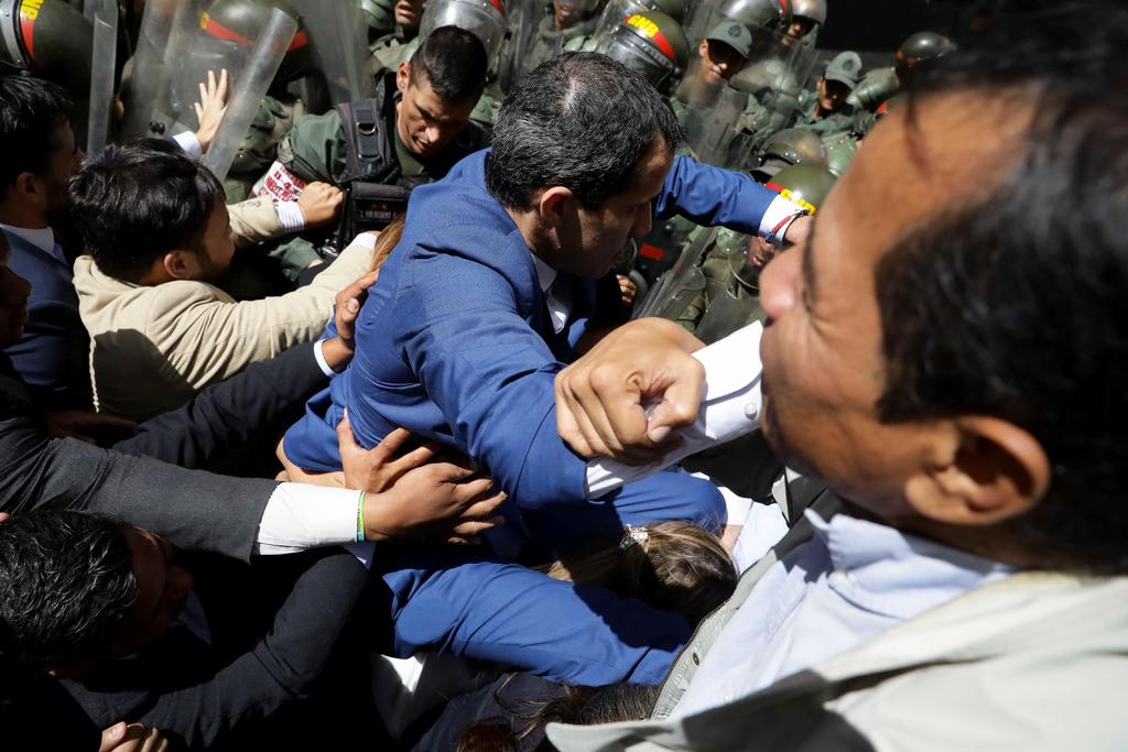 El líder opositor venezolano, Juan Guaidó, acompañado de un grupo de opositores, forcejean con la policía al ver impedida su entrada a la sede de la Asamblea Nacional este domingo, en Caracas. (EFE)
