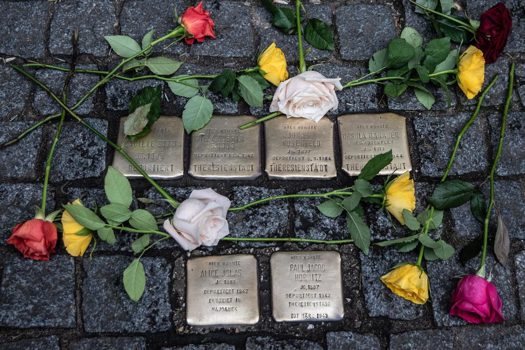Sobre las placas con el nombre y fecha de deportación de las víctimas del exterminio nazi se colocaron decenas de flores. (EFE)