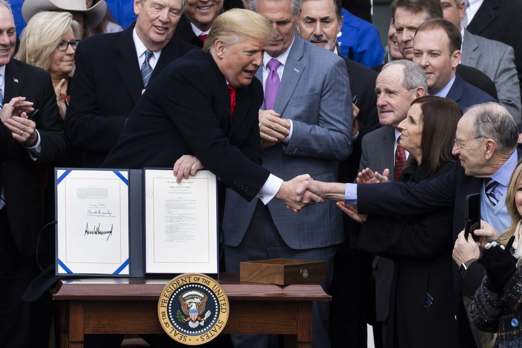 En la firma de la ratificación del T-MEC, Donald Trump le da la mano al republicano Chuck Grassley, en una ceremonia donde estuvo bromeando a pesar de que enfrenta un juicio político en su contra. (EFE) 