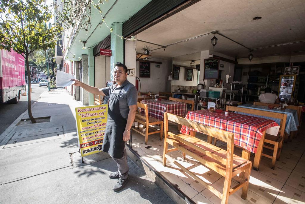 Bajo los rayos del sol y con la preocupación de que no hay clientes, Andrés Hernández sale de la cocina económica 'María Isabel' para llamar la atención de la gente. (EL UNIVERSAL)