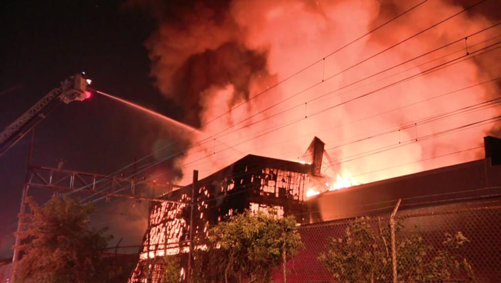 Cientos de bomberos trataban de sofocar las llamas tras el estallido de un incendio en un enorme galpón en el norte de Filadelfia el domingo. (ESPECIAL) 