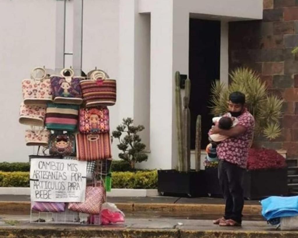 Por medio del Internet se difundió la fotografía de un artesano pidiendo artículos para su bebé, sosteniéndolo en sus brazos mientras trabaja, por lo que de inmediato decenas de mexicanos se unieron para llevarle ayuda. (Facebook) 
