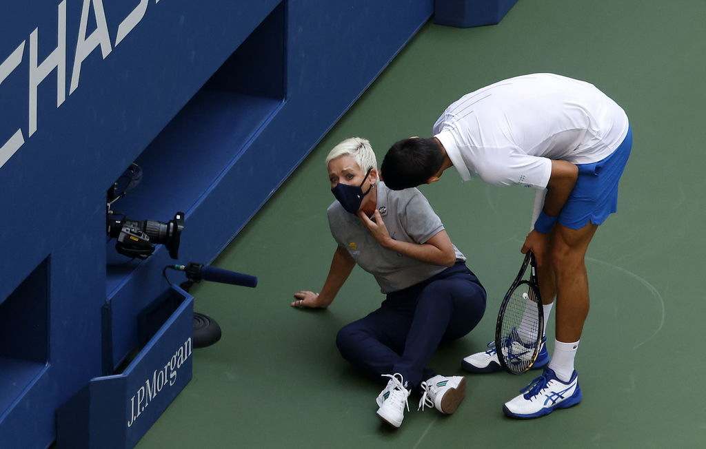 Novak Djokovic asiste a la jueza de línea a la cual le dio un pelotazo en la garganta, motivo por el cual fue descalificado. (EFE)