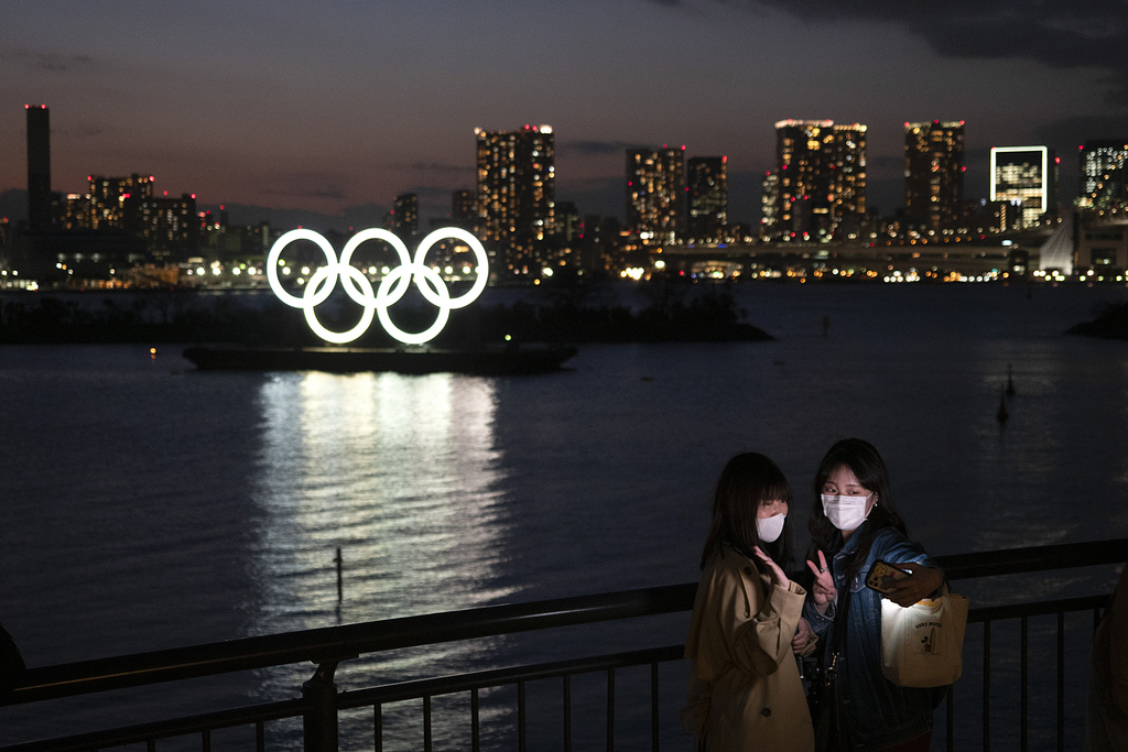 En esta imagen de marzo de 2020, dos mujeres se toman una foto con los aros olímpicos en el fondo en Tokio. (AP)