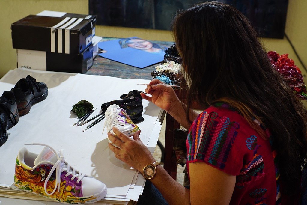 Doris Arellano Manzo mientras pinta tenis con motivos del tradicional Día de Muertos. (EFE)