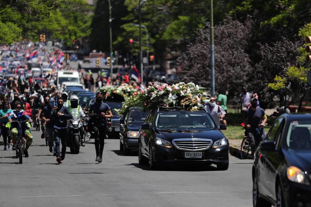 Una cadena humana separa la gente agolpada en las aceras del paso de vehículos en el camino hacia el Palacio Legislativo, de donde partirá hacia el cementerio de La Teja. (EFE)