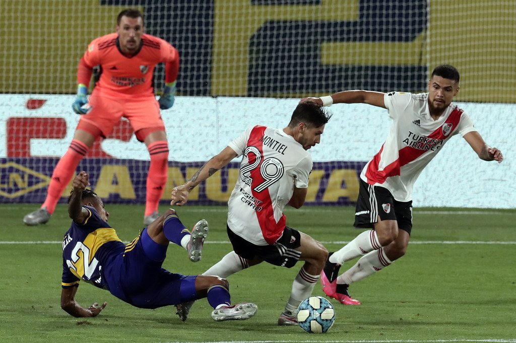 El colombiano Sebastian Villa (i) de Boca Juniors disputa el balón ante Gonzalo Montiel (c) de River Plate, en una intensa confrontación.