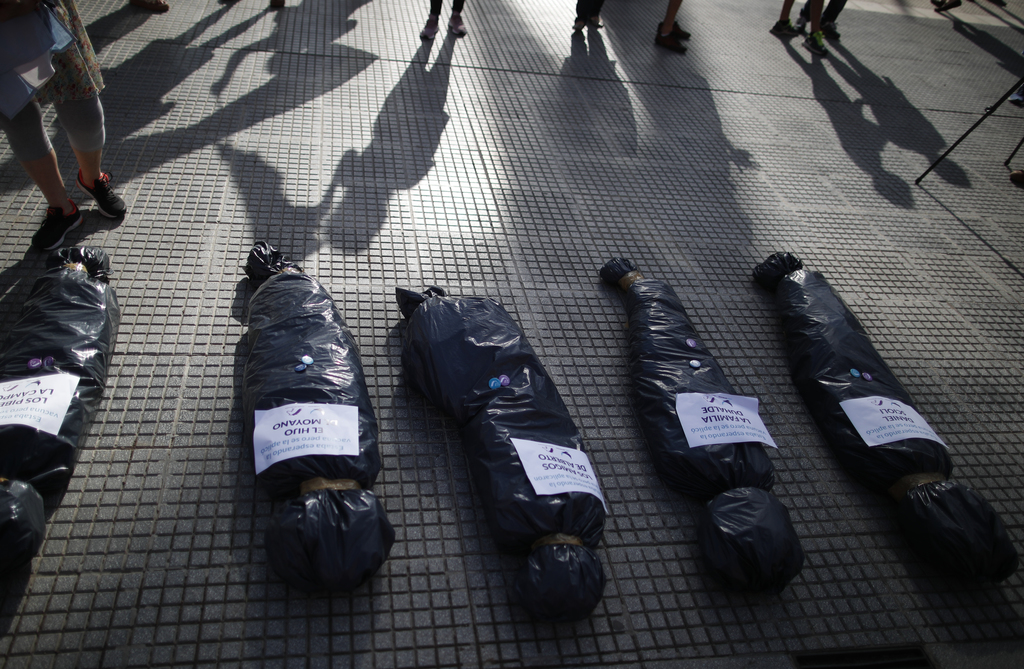 Los manifestantes simularon, usando bolsas, cuerpos de personas fallecidas con los nombres de aquellos que recibieron las vacunas . (AP) 