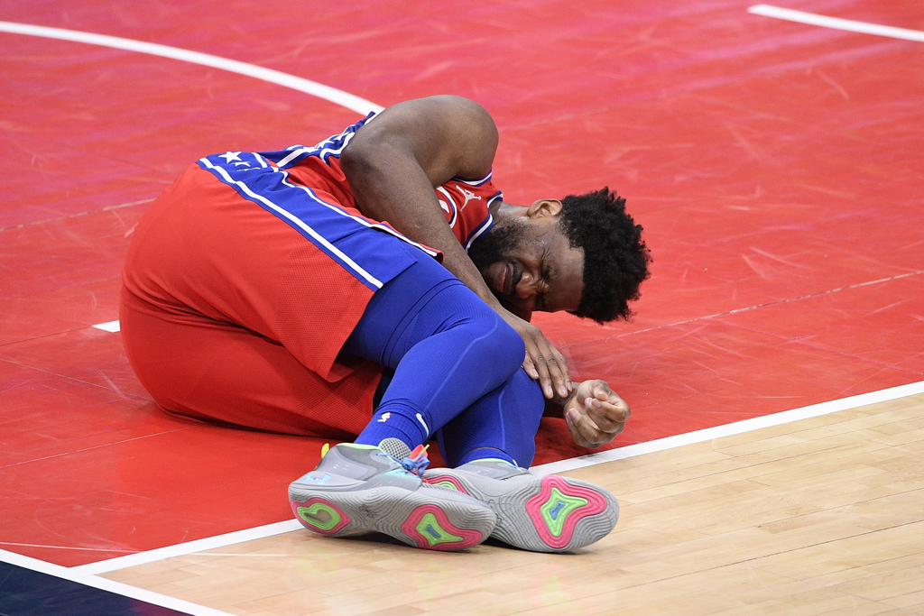 Joel Embiid se queja tras sufrir una lesión en la rodilla izquierda en el juego de ayer ante Wizards. (AP)