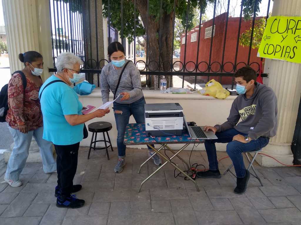El joven Martín, su novia y su madre, improvisaron un centro de impresión en las afueras de la Facultad de Derecho de la UAdeC. (ANGÉLICA SANDOVAL)