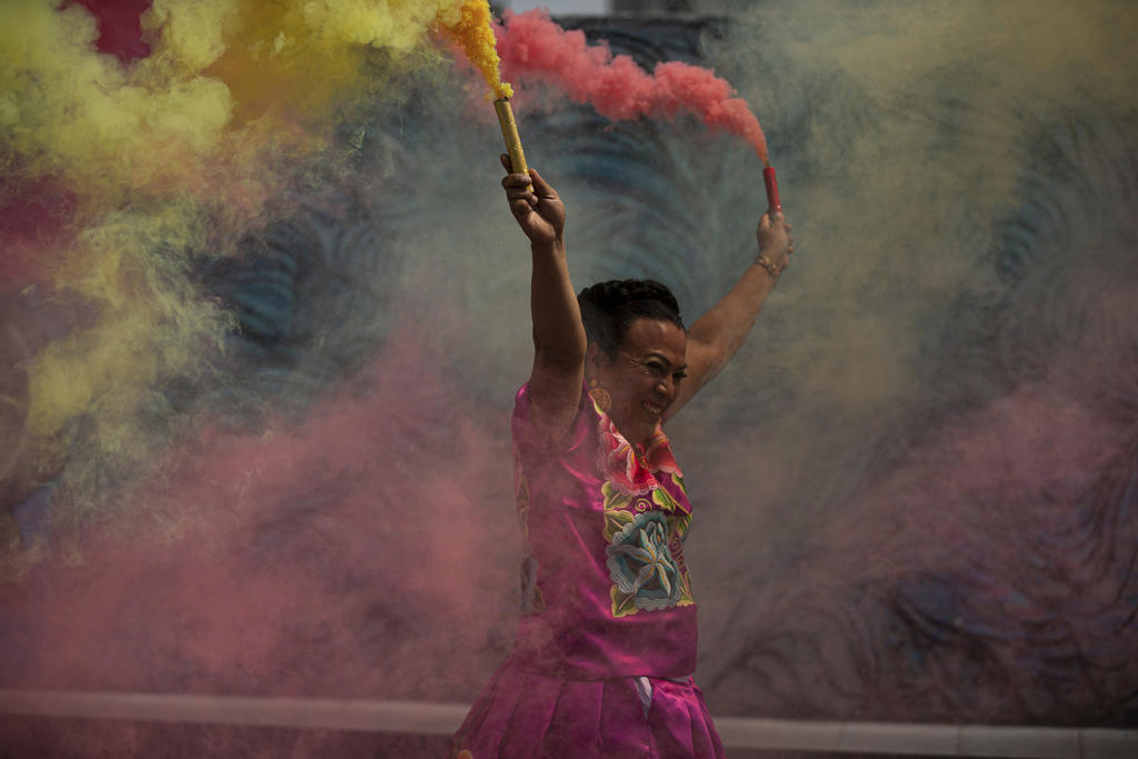 Marven, una mujer transgénero del estado de Oaxaca, lanza coloridas bengalas de humo durante su evento de campaña para un asiento en el Congreso de la Ciudad de México, afuera de un restaurante el sábado 29 de mayo de 2021. (AP Foto/Fernando Llano)